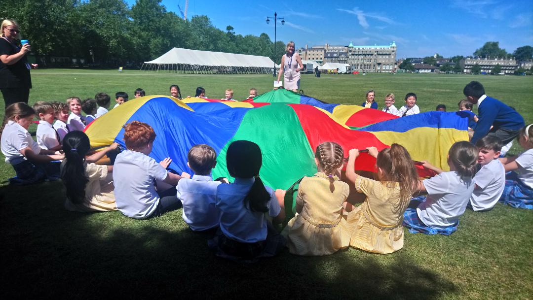 Students holding a multicoloured parachute