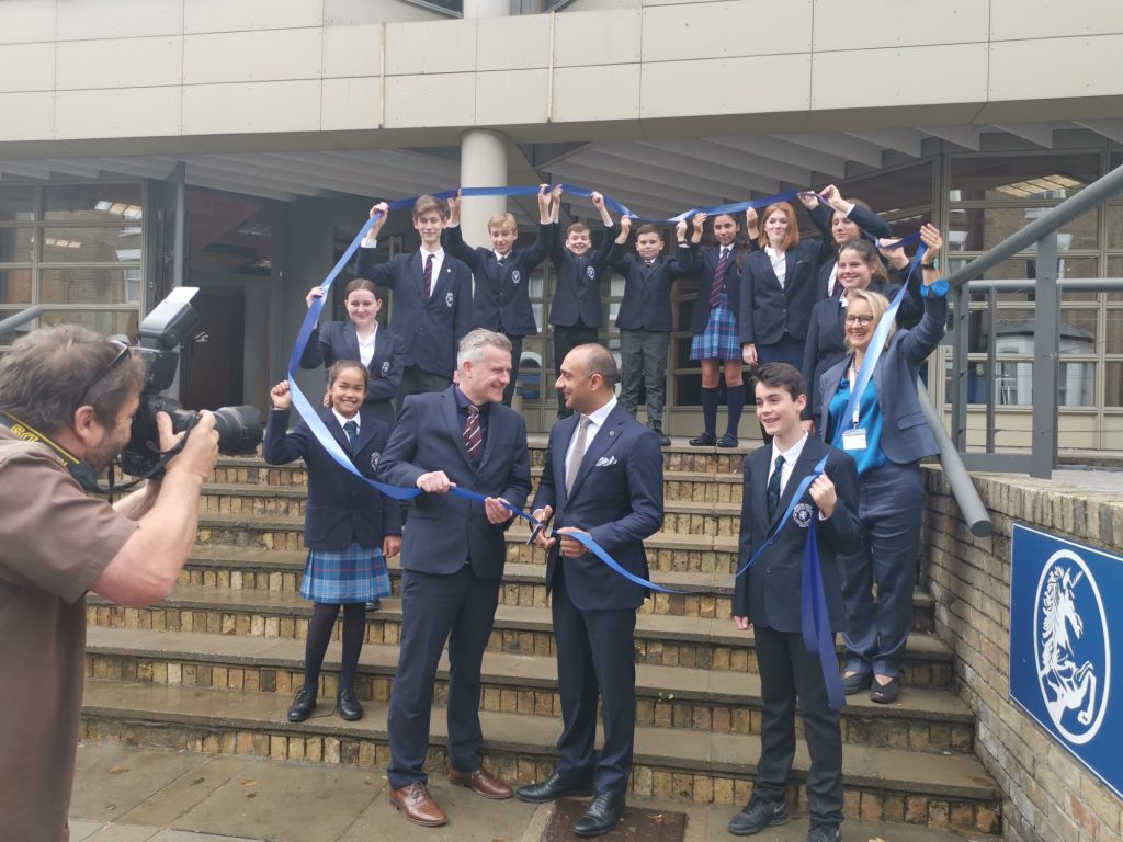 students and teachers holding a ribbon