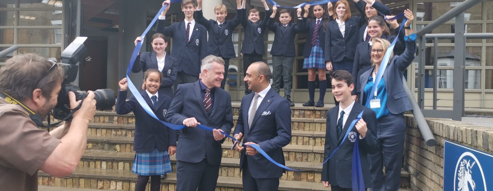 students and teachers holding a ribbon