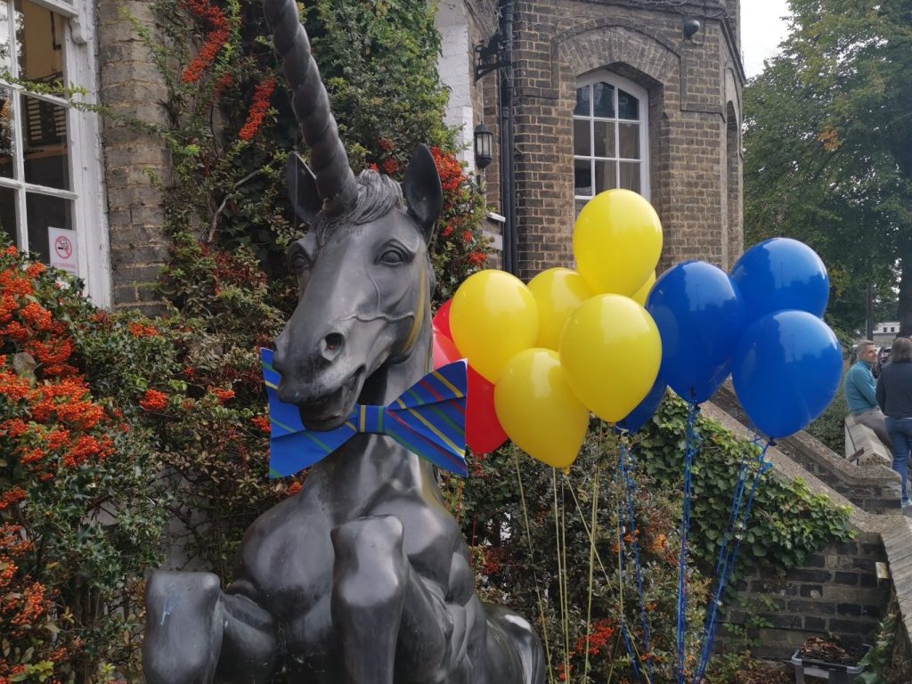 yellow and blue balloons with a unicorn statue