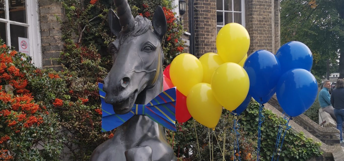yellow and blue balloons with a unicorn statue