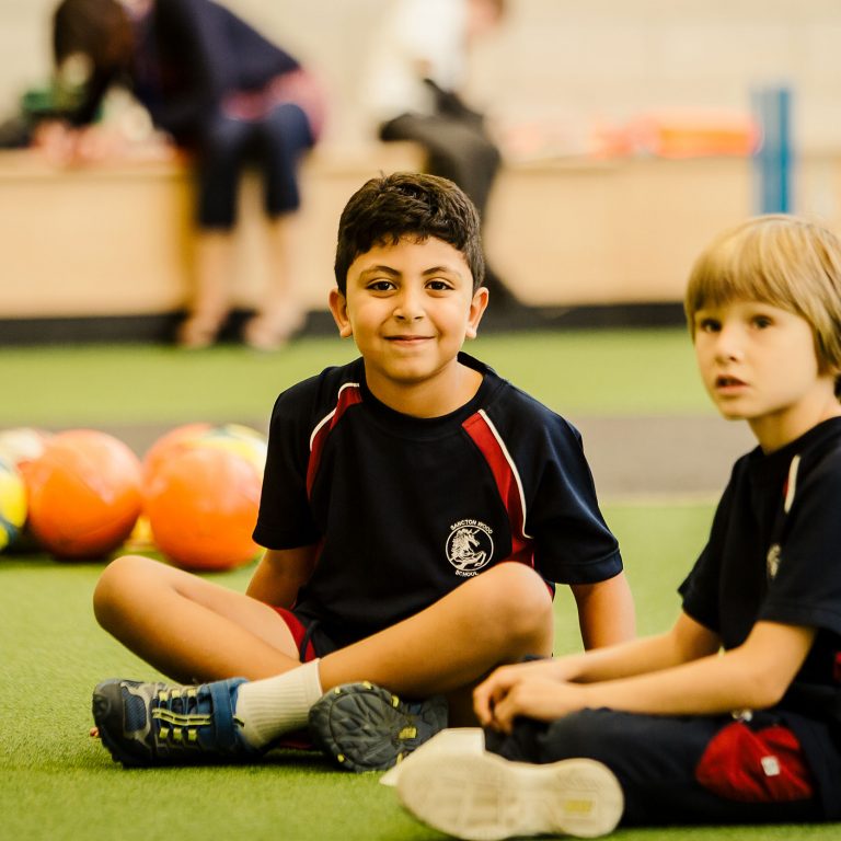 two children sitting on the floor in their PE kits