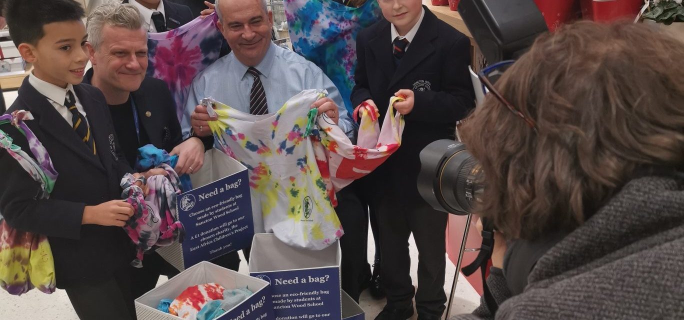 teacher holding bags children have made with tie dye