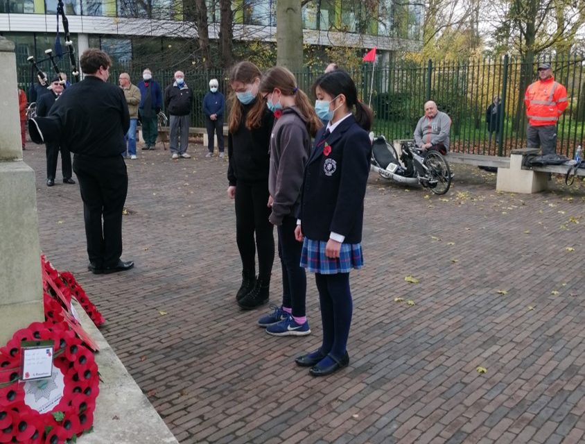 children standing infront of poppy wreaths paying their respects on remembrance day