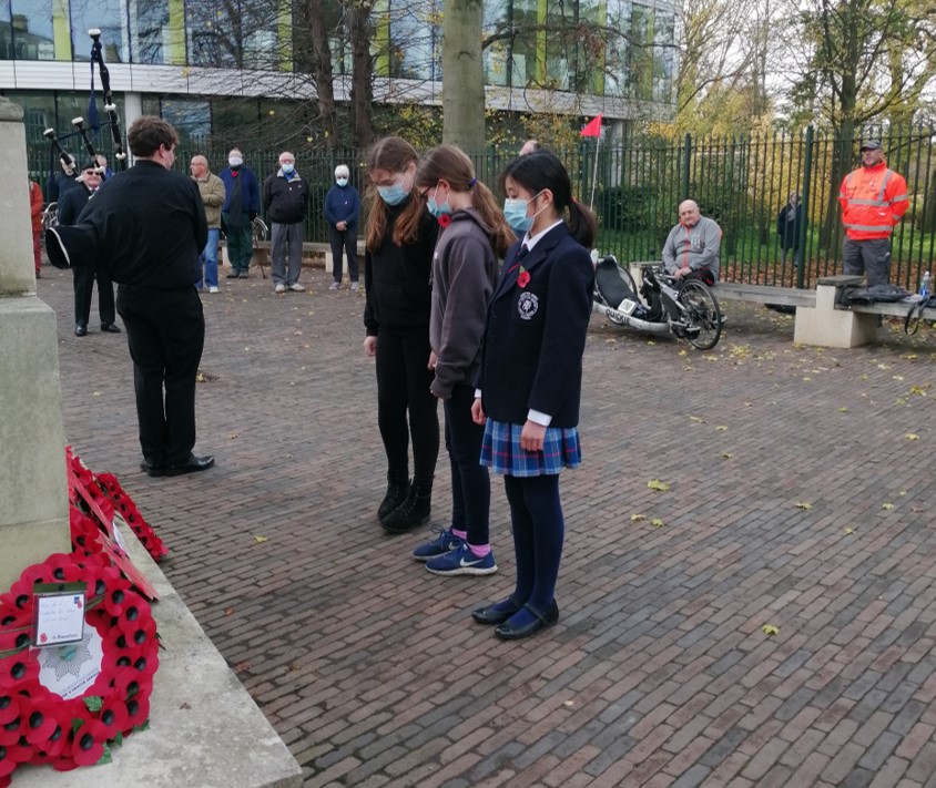 children standing infront of poppy wreaths paying their respects on remembrance day