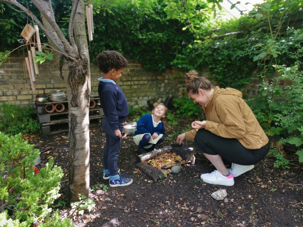 children pretending to start a fire with their teacher