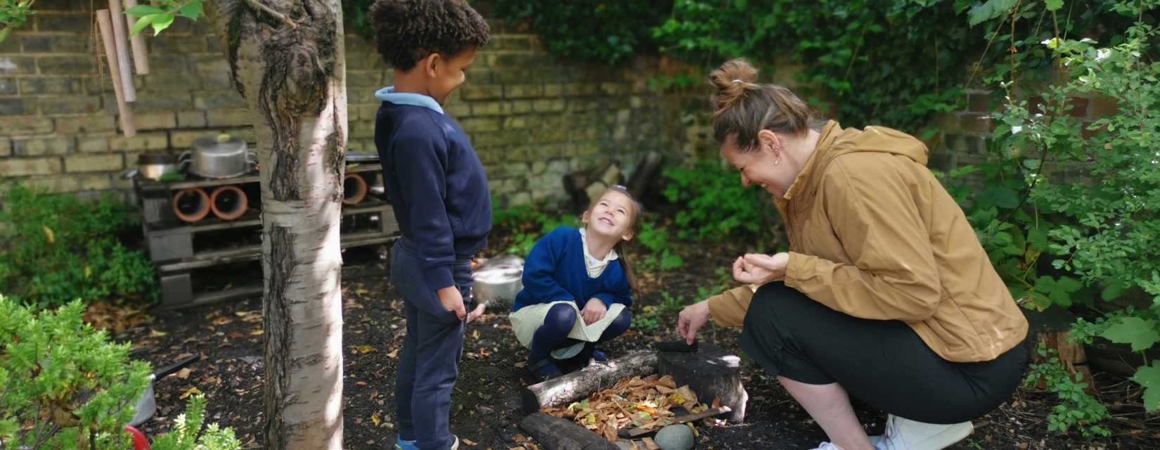 children pretending to start a fire with their teacher