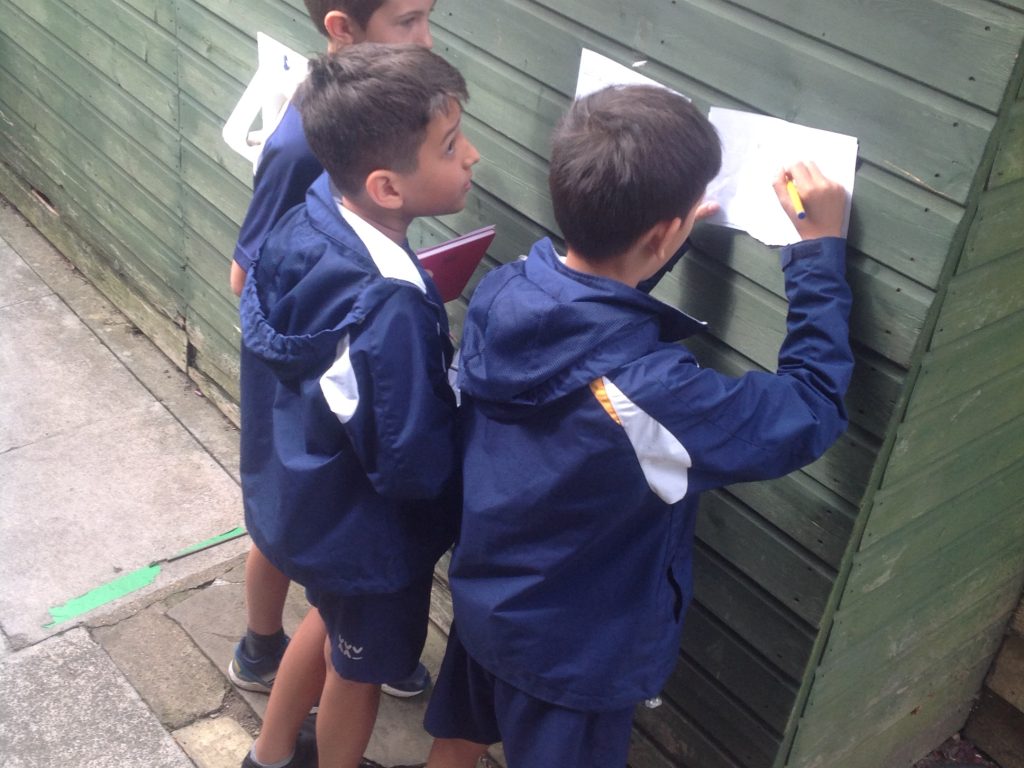 children leaning against a shed to write