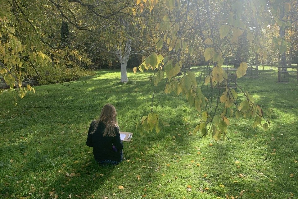 child sitting on grass with a clip board