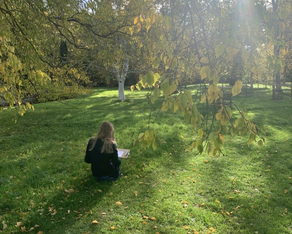 child sitting on grass with a clip board